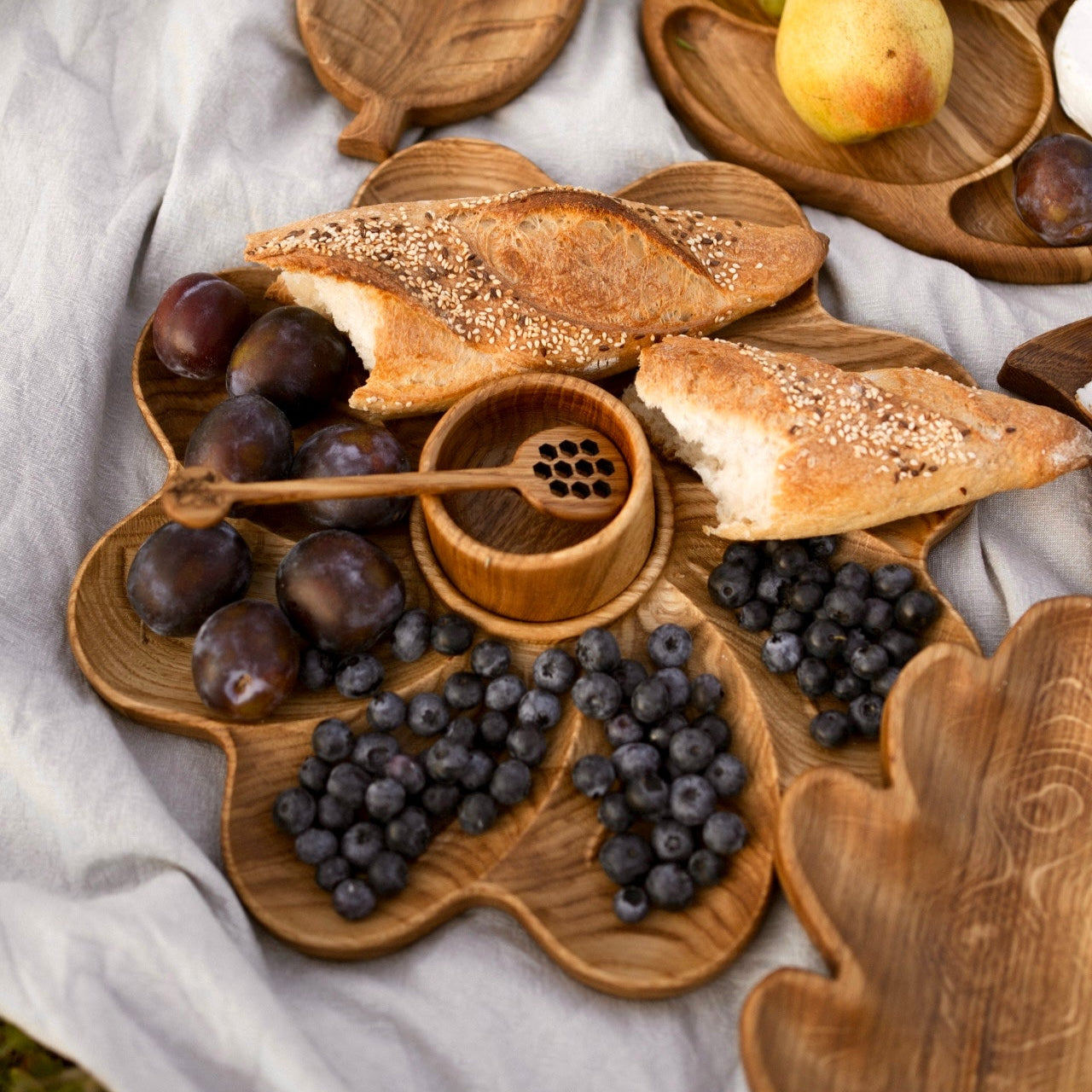 Picnic-ready oak plate with bowl and dipper on natural fabric background